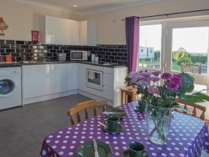 a kitchen with a purple table with flowers on it at Llainfawr Cottage Apartment Fishguard in Letterston +3 photos