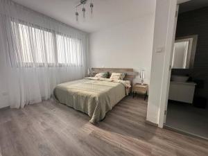 um quarto com uma cama e uma grande janela em Cozy 3 Bedroom Apartment 300M from the SEA em Lárnaca
