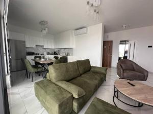 a living room with a green couch and a kitchen at Cozy 3 Bedroom Apartment 300M from the SEA in Larnaka