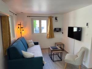 a living room with a blue couch and a tv at Gîte Les Lilas, centre Alsace, avec jacuzzi in Mackenheim