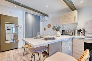 uma cozinha com um grande balcão branco e cadeiras em nid douillet près du vieux port em Marselha