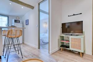 uma sala de estar com uma televisão de ecrã plano e uma mesa em nid douillet près du vieux port em Marselha