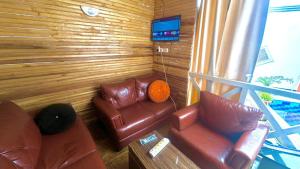 a living room with two leather couches and a television at 001 Apartments in Oshogbo