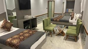 a hotel room with two beds and a tv and chairs at Hotel Cottage Yes Please - New Delhi in New Delhi
