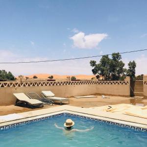 a swimming pool with a hat in the water at riad luz merzouga in Merzouga
