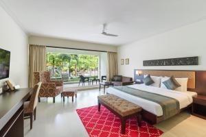 um quarto de hotel com uma cama grande, uma secretária e cadeiras em TatSaraasa Resort & Spa, Udaipur em Udaipur