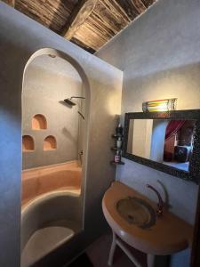 een badkamer met een bad, een wastafel en een spiegel bij Palais D'Ouzoud in Azilal