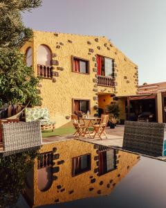 a house with chairs and a reflection in the water at Hostel Los Amigos by Youroom in La Mareta