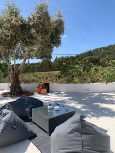 eine Terrasse mit Sonnenschirmen, einem Tisch und einem Baum in der Unterkunft Monte do Pereiro in Santiago do Cacém
