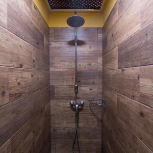 a shower in a bathroom with wooden walls at Hostel Los Amigos by Youroom in La Mareta