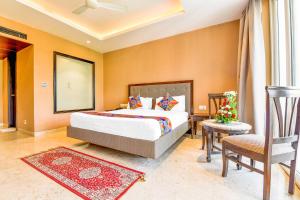 a hotel room with a bed and a chair at FabHotel Prime The King's Court Calangute with Pool and Bar in Calangute