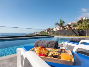 een dienblad met eten op een tafel naast een zwembad bij Villa Luxe by Atlantic Holiday in Ribeira Brava