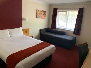 Days Inn Southampton Rownhams في ساوثهامبتون: غرفه فندقيه بسرير وكرسي