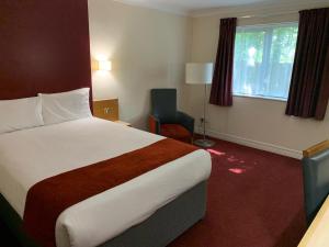 una habitación de hotel con una cama grande y una silla en Days Inn Southampton Rownhams en Southampton