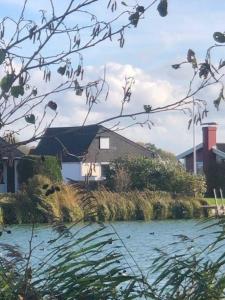 a house sitting next to a body of water at Freistehendes Ferienhaus in Eckwarderhörne mit schönem Garten in Butjadingen