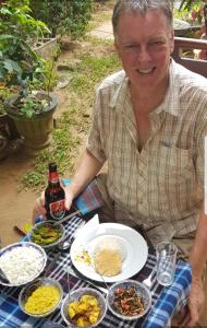 een man aan een tafel met borden eten bij Lucky's Homestay in Maho