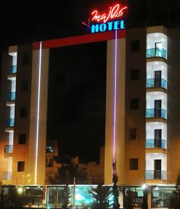 a hotel building with a neon hotel sign at night at Majliss Hotel Downtown in Rabat