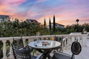 a table and chairs on a balcony with a sunset at Villa Markota!200m from the SEA! in Promajna