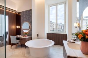 a bathroom with a tub and a table and a desk at Palazzo Cordusio, a Gran Melia Hotel in Milan