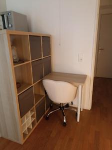 a desk and a book shelf with a white chair at Studio tout confort Massy-Paris in Massy