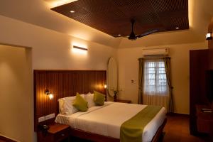 een slaapkamer met een groot bed en een raam bij KTDC Kumarakom Gateway Resort in Alleppey