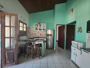 cocina con paredes verdes, nevera y taburetes en Casa no atalaia na rua atalho, en Salinópolis