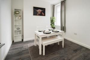 uma sala de jantar branca com uma mesa e cadeiras brancas em Dunraven by StayStaycations em Port Talbot