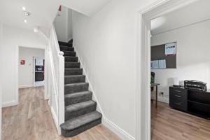 a staircase in a home with white walls and wood floors at Sudbury heights Guest House in Harrow on the Hill