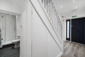 a white bathroom with a toilet and a staircase at Sudbury heights Guest House in Harrow on the Hill