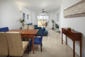 a dining room and living room with a table and blue chairs at Relaxation, GOLF and Beach in Caleta De Velez