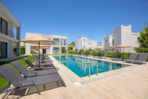 a swimming pool with chairs and umbrellas next to a building at Ben Houses Family in Bodrum City