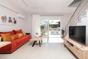 ein Wohnzimmer mit einem roten Sofa und einem Flachbild-TV in der Unterkunft Villa Riza Sun by Villa Plus in Katastárion