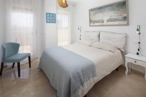 um quarto branco com uma cama e uma cadeira em Relaxation, GOLF and Beach em Caleta De Velez