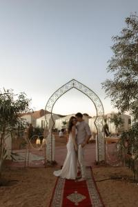 Una novia y un novio de pie bajo un arco en Desert Coast Opulent Camp en Merzouga