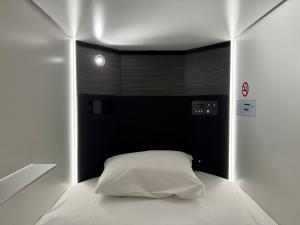 a bedroom with a white bed with a black headboard at カプセルホテル鈴森屋 Capsule Hotel Suzumoriya in Tokyo