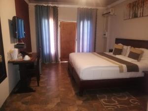 PalapyeにあるThe Tamek Palace Hotelのベッドと机とテレビのある寝室