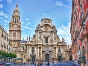 a large stone building with two towers on a street at Apartamur Chic 115 in Murcia