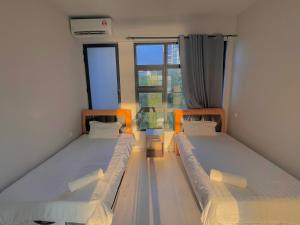 two beds in a small room with a window at SUNRISE JESSELTON QUAY NEAR SURIA GAYA STREET Jesselton Point in Kota Kinabalu