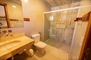 a bathroom with a shower and a toilet and a sink at Chalés Estilo de Campos in Campos do Jordão