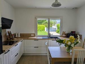a kitchen with white cabinets and a table with a vase of flowers at La Sapinière in Perros-Guirec