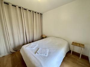Un pequeño dormitorio con una cama blanca y una ventana en *Esprit Littoral* T2 Terrasse Parking Wifi, en Quimper
