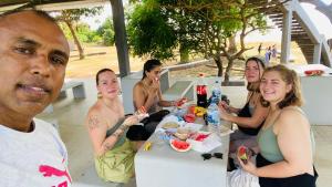 un grupo de personas sentadas alrededor de una mesa comiendo comida en Owin Rose Yala Safari Hotel en Tissamaharama