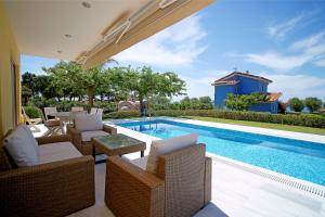 a swimming pool with wicker chairs and a swimming pool at Dimitras Villas in Kalón Nerón