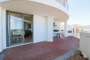 a balcony with sliding glass doors and a dining room at 506 Hibernian Towers Luxury Self Catering Apartment Strand Cape Town South Africa in Cape Town