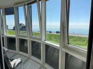 een kamer met vier ramen met uitzicht op de oceaan bij Apartment 123 in Wilhelmshaven