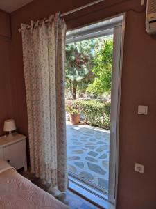 - une chambre avec une porte coulissante en verre donnant sur une terrasse dans l'établissement Drossinos Studios, à Poros
