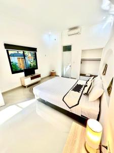 a bedroom with a large bed and a flat screen tv at THE SUN BALI VILLA’S in Kuta