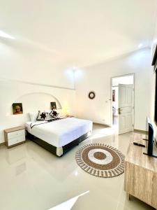 a white bedroom with a large bed and a television at THE SUN BALI VILLA’S in Kuta