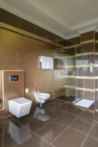a bathroom with a toilet and a glass shower at GemSuites Riverside in Nairobi