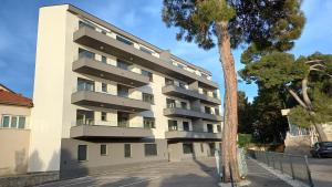 a tall white building with a tree in front of it at Modern Apartment Zablaće in Zablaće